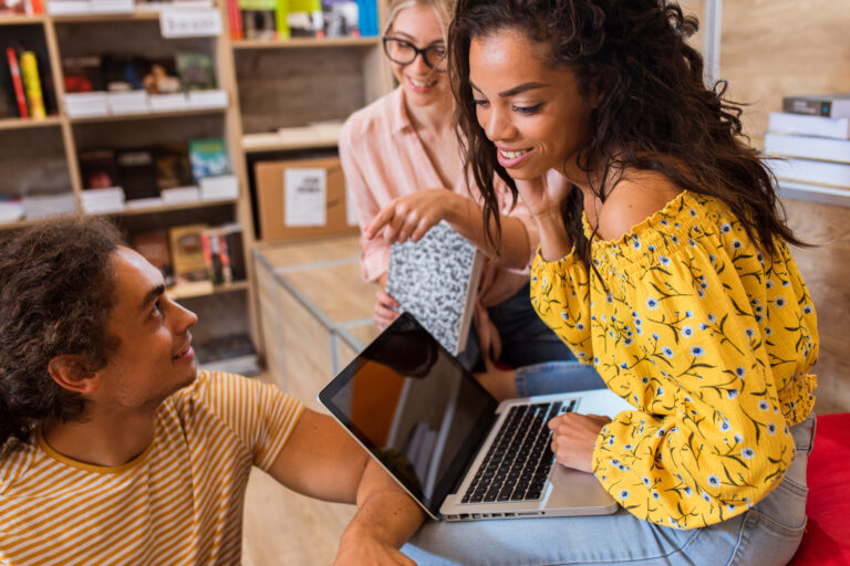 Three young students sitting on the floor in the library learnin