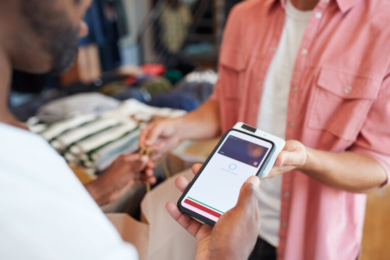 Man In Clothing Store Making Contactless Payment With App On Mobile Phone