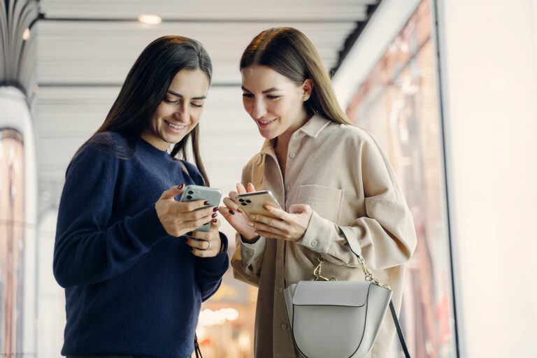 two girlfriends using their cellphone while exploring a new city at night